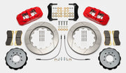Wilwood AERO6 brake kit: Pair of red calipers, slotted rotor rings, hats with their inner faces visible, pads, hoses, brackets and mounting fasteners arranged on white; 14-inch front brake setup for BMW E46 M3.