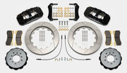 Wilwood AERO6 brake kit: Pair of black calipers, slotted rotor rings, hats with their inner faces visible, pads, hoses, brackets and mounting fasteners arranged on white; 14-inch front brake setup for BMW E46 M3.