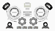Wilwood Dynalite front brake kit, TR4A / TR250 / TR6, 11-inch SRP rotors: Parts layout with two black Dynalite calipers, drilled & slotted rotor rings, separate black hats, pads, brackets and fasteners, with curved flexlines visible.