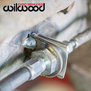 Wilwood weld-on axle brake-line tab supporting the hose-to-hard-line junction, close view