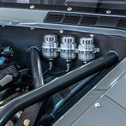 Wilwood engine-bay installation example showing three silver-colored finned reservoirs on a common bracket