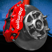 Wilwood red Superlite front caliper mounted beside an undrilled rotor and five-stud hub in a Porsche 911 brake installation reference