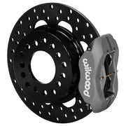 Wilwood rear gray Dynalite caliper beside an 11.44-inch drilled rotor, angled assembly for Olds/Pontiac housing end