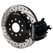 Wilwood rear black CPB caliper beside a 12.88-inch drilled/slotted rotor, angled assembly for Mustang solid axle, 3.25-inch offset