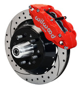 Wilwood front red Superlite 6R caliper beside a 12.88-inch drilled/slotted rotor, angled assembly for early Ford/Mercury disc spindles