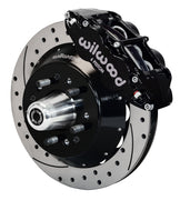 Wilwood front black Superlite 6R caliper beside a 12.88-inch drilled/slotted rotor, angled assembly for later Ford/Mercury disc spindles