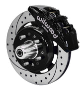 Wilwood front black Dynapro 6 caliper beside a 12.19-inch drilled/slotted rotor, angled assembly for Tri-Five Chevrolet drum spindle