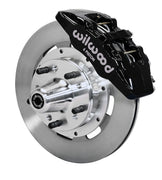 Wilwood front black Dynapro 6 caliper beside a 12.19-inch plain-face rotor, angled assembly for Mopar B/E-body drum spindle