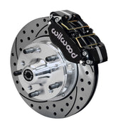 Wilwood GM and Ridetech pin-spindle front single-side assembly showing a black Dynapro dust-boot caliper beside an 11-inch drilled-and-slotted rotor and protruding wheel studs