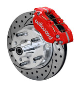 Wilwood GM and Ridetech pin-spindle front single-side assembly showing a red Dynapro dust-boot caliper beside an 11-inch drilled-and-slotted rotor and protruding wheel studs