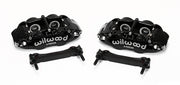 Wilwood pair of black four-piston rear calipers beside two mounting brackets; no rotors shown