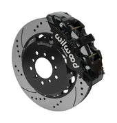 Wilwood AERO6 brake kit: A black caliper beside a drilled-and-slotted rotor mounted to a black five-hole hat, viewed at an angle; 14-inch front brake setup for BMW E46 M3.