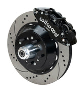 Wilwood Superlite 6R brake kit: A black caliper beside a drilled-and-slotted rotor and deep black hat over a wheel hub, with visible studs and a polished dust cap; 14-inch front brake setup for 1957–1967 F-100.