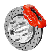 Wilwood red four-piston front caliper beside an 11-inch drilled-and-slotted rotor with projecting wheel hub for the early A-body 11-inch front installation