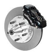 Wilwood black four-piston front caliper beside an 11-inch plain-face rotor with projecting wheel hub for the early A-body 11-inch front installation