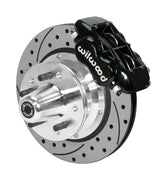 Wilwood black four-piston front caliper beside an 11-inch drilled-and-slotted rotor with projecting wheel hub for the later Mopar 11-inch front installation