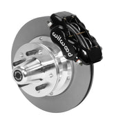 Wilwood black four-piston front caliper beside an 11-inch plain-face rotor with projecting wheel hub for the later Mopar 11-inch front installation
