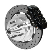 Wilwood black four-piston front caliper beside a 12.19-inch drilled-and-slotted rotor with projecting wheel hub for the later Mopar 12.19-inch front installation