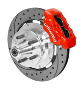Wilwood red four-piston front caliper beside a 12.19-inch drilled-and-slotted rotor with projecting wheel hub for the later Mopar 12.19-inch front installation