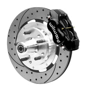 Wilwood black four-piston front caliper beside a 12.19-inch drilled-and-slotted rotor with projecting wheel hub for the CPP Tri-Five 12.19-inch front installation