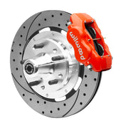 Wilwood red four-piston front caliper beside a 12.19-inch drilled-and-slotted rotor with projecting wheel hub for the CPP Tri-Five 12.19-inch front installation