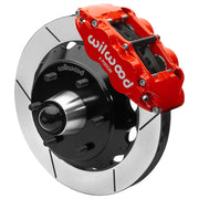 Wilwood red front caliper beside the assembled 13.06-inch slotted rotor for the Chevrolet/GMC six-lug 13.06-inch Superlite drop-spindle brake conversion, with the hub and wheel studs visible