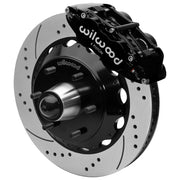 Wilwood black front caliper beside the assembled 14.00-inch drilled and slotted rotor for the Chevrolet/GMC six-lug 14-inch Superlite drop-spindle brake conversion, with the hub and wheel studs visible