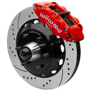 Wilwood red front caliper beside the assembled 14.00-inch drilled and slotted rotor for the Chevrolet/GMC six-lug 14-inch Superlite drop-spindle brake conversion, with the hub and wheel studs visible