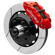 Wilwood red front caliper beside the assembled 14.00-inch slotted rotor for the Chevrolet/GMC six-lug 14-inch Superlite drop-spindle brake conversion, with the hub and wheel studs visible