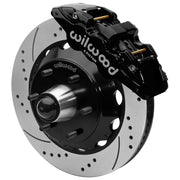 Wilwood black front caliper beside the assembled 14.00-inch drilled and slotted rotor for the Chevrolet/GMC six-lug AERO6 drop-spindle brake conversion, with the hub and wheel studs visible