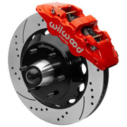 Wilwood red front caliper beside the assembled 14.00-inch drilled and slotted rotor for the Chevrolet/GMC six-lug AERO6 drop-spindle brake conversion, with the hub and wheel studs visible