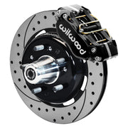 Wilwood front Dynapro brake kit for Tri-Five ProSpindle Dynapro configuration: Assembled drilled and slotted rotor and black hat with a black Dynapro caliper, projecting hub, five studs and a silver dust cap.