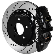 Wilwood black AERO4 rear caliper beside the assembled 14.00-inch drilled and slotted rotor and internal-parking-brake hat for Chevrolet and GMC C1500